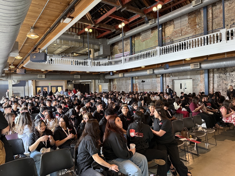 A large group of students sits in a historic, multi-level theater for a Latinos In Action event presentation.