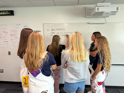 Future Educator students writing traits of good teachers on the whiteboard during the first day of class.