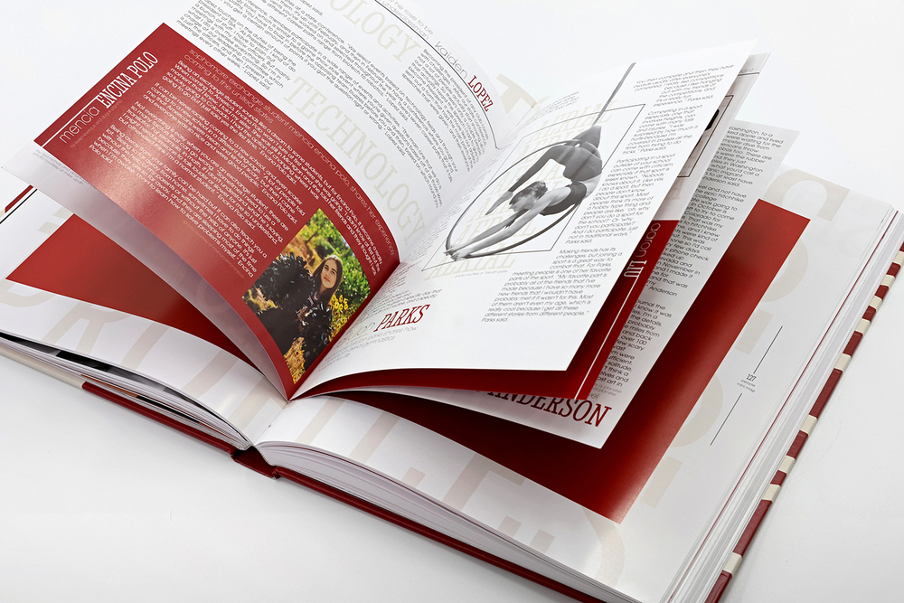A yearbook opened to a center page. Black-and-white and color photos are visible on white pages with black and dark red text as well as red sections with white text.