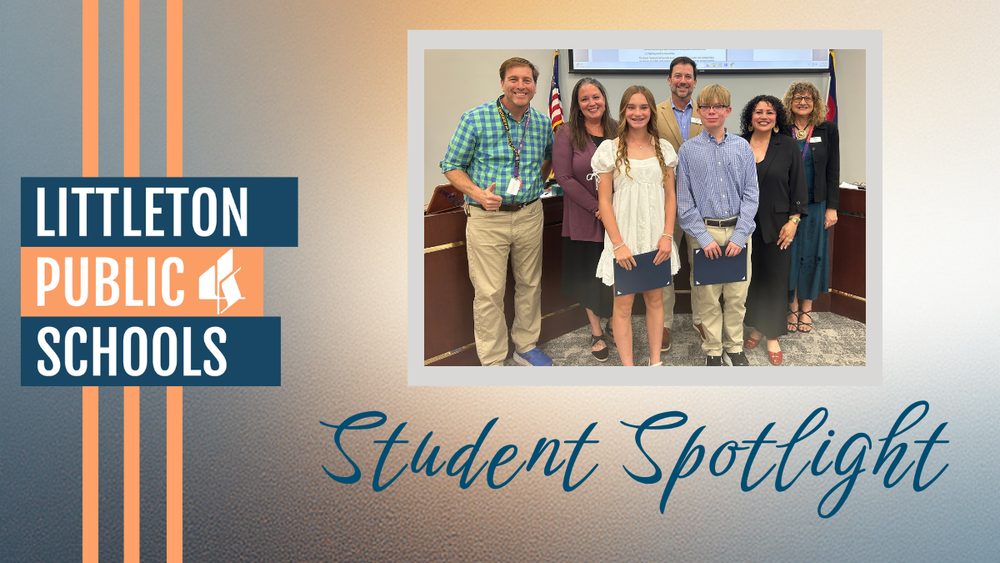 Two middle school students stand with the Board of Education during the Student Spotlight segment of a Board meeting in the LPS Boardroom.