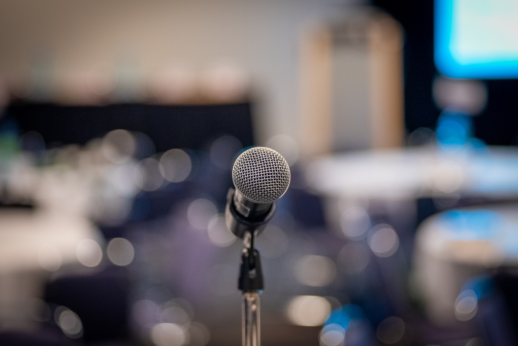 A microphone in focus in the foreground with a public venue out-of-focus in the background