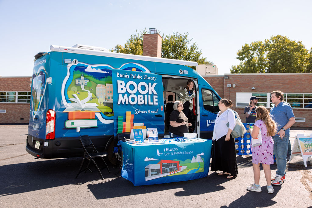 BLue Bemis Library Book Mobile parked on black top at community resource expo, serving community members with more information on their library card program