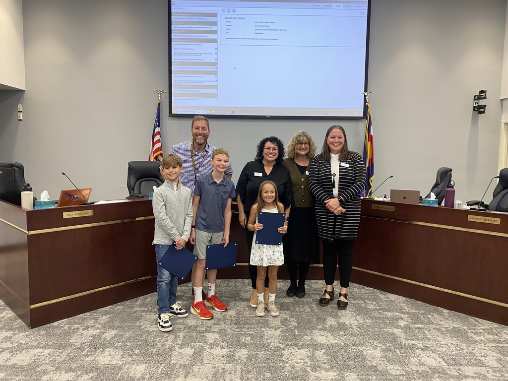 Three students from Wilder stand with Board of Education members in the LPS Boardroom.