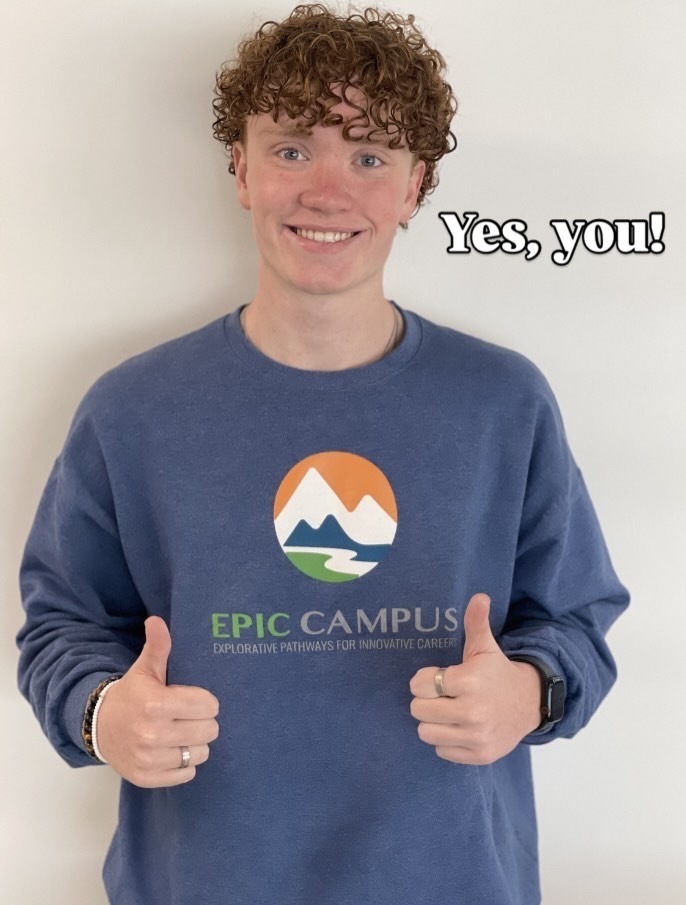 A smiling student with curly hair gives two thumbs up while wearing a blue EPIC Campus sweatshirt. The sweatshirt features a mountain and river logo above the words “EPIC CAMPUS” and “Explorative Pathways for Innovative Careers.” Text in the top right corner reads “Yes, you!” in bold black font with a white outline.