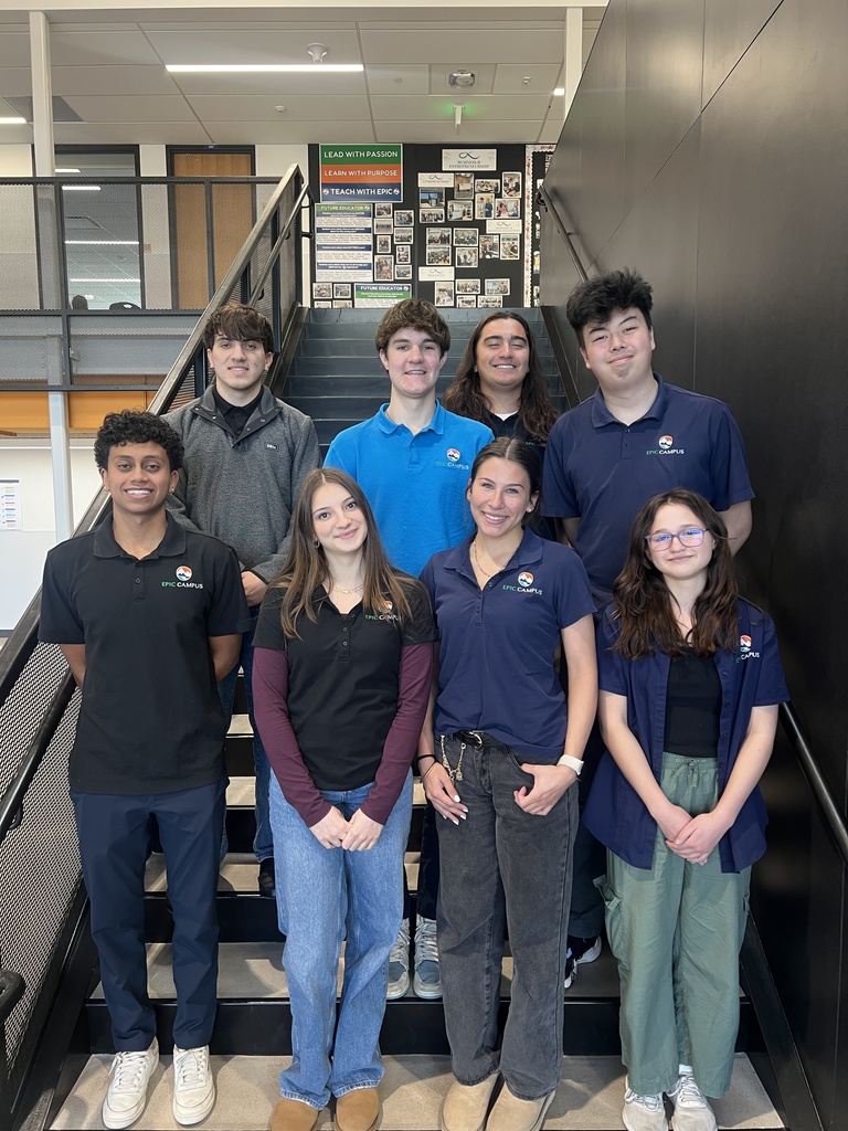 Eight high school students pose on a stairwell for a group photo. They are wearing EPIC Campus uniforms and casual clothes, smiling toward the camera.