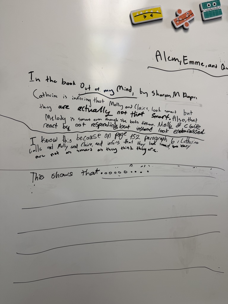 A whiteboard displays student writing about the book “Out of My Mind” by Sharon M. Draper, explaining character inferences about Molly, Claire, and Melody, with space below labeled “This shows that…” for further analysis.