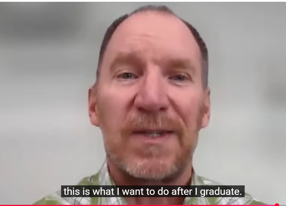 Head-and-shoulders view of a middle-aged man with short hair and a trimmed beard speaking against a plain light-colored background. On-screen caption reads, “this is what I want to do after I graduate.”