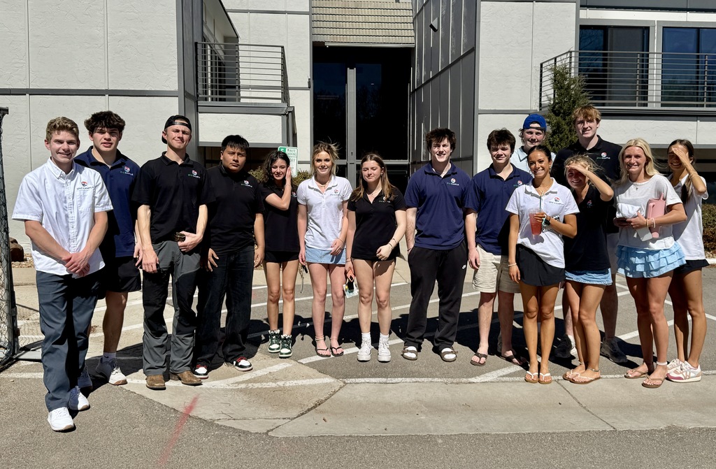 A second group of high school students stands outside the same building entrance, smiling and facing the camera. Students wear a mix of EPIC Campus polos and casual clothing such as shorts and skirts. One student holds a drink, and another shades their eyes from the sun. The building entrance and railings are visible in the background.