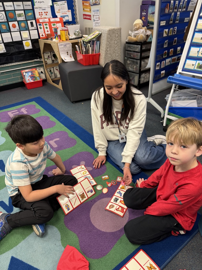 Three children sitting on the floor, one holding a puzzle, and a woman sitting nearby.