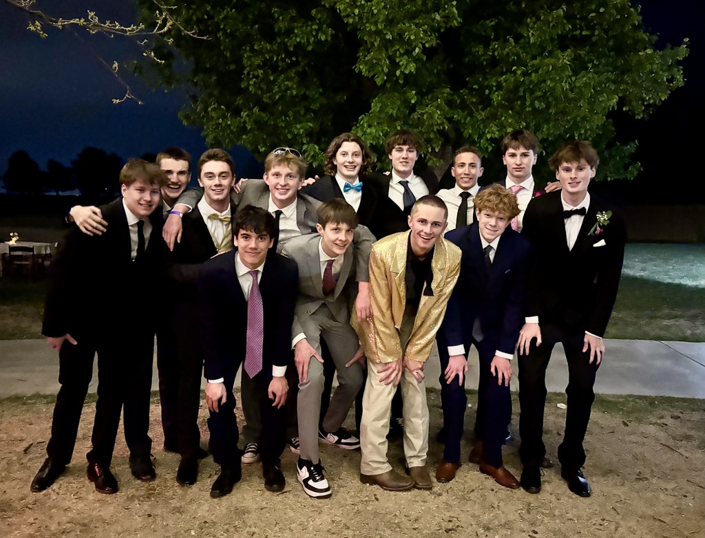 A group of young people in formal wear, including suits and ties, posing for a photo.