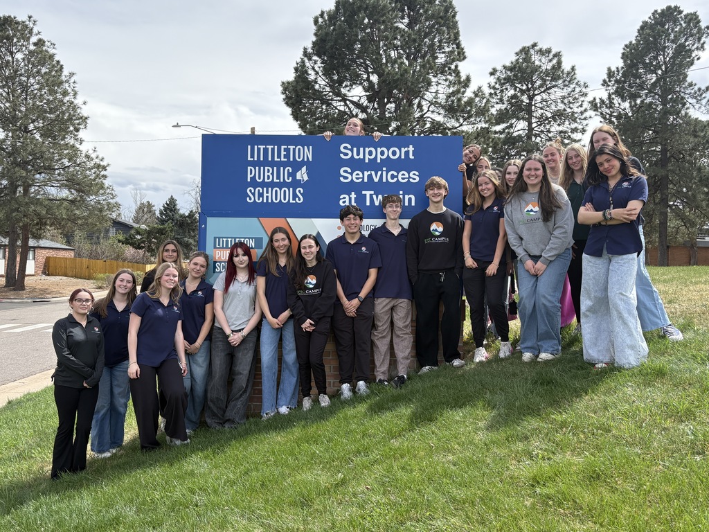 Group of students and staff stand in front of a blue sign that reads "LITTLETON PUBLIC 4 SCHOOLS" with "Support Services at Twin".