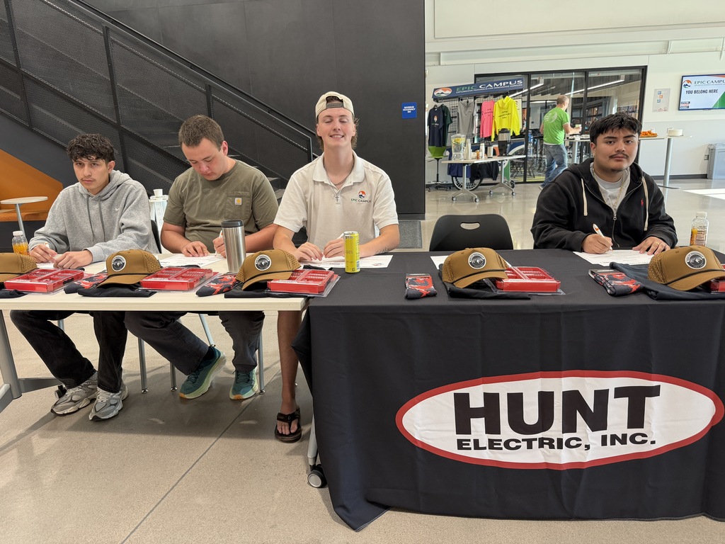 Five people sitting at a table with a sign for Hunt Electric, Inc. in the foreground.