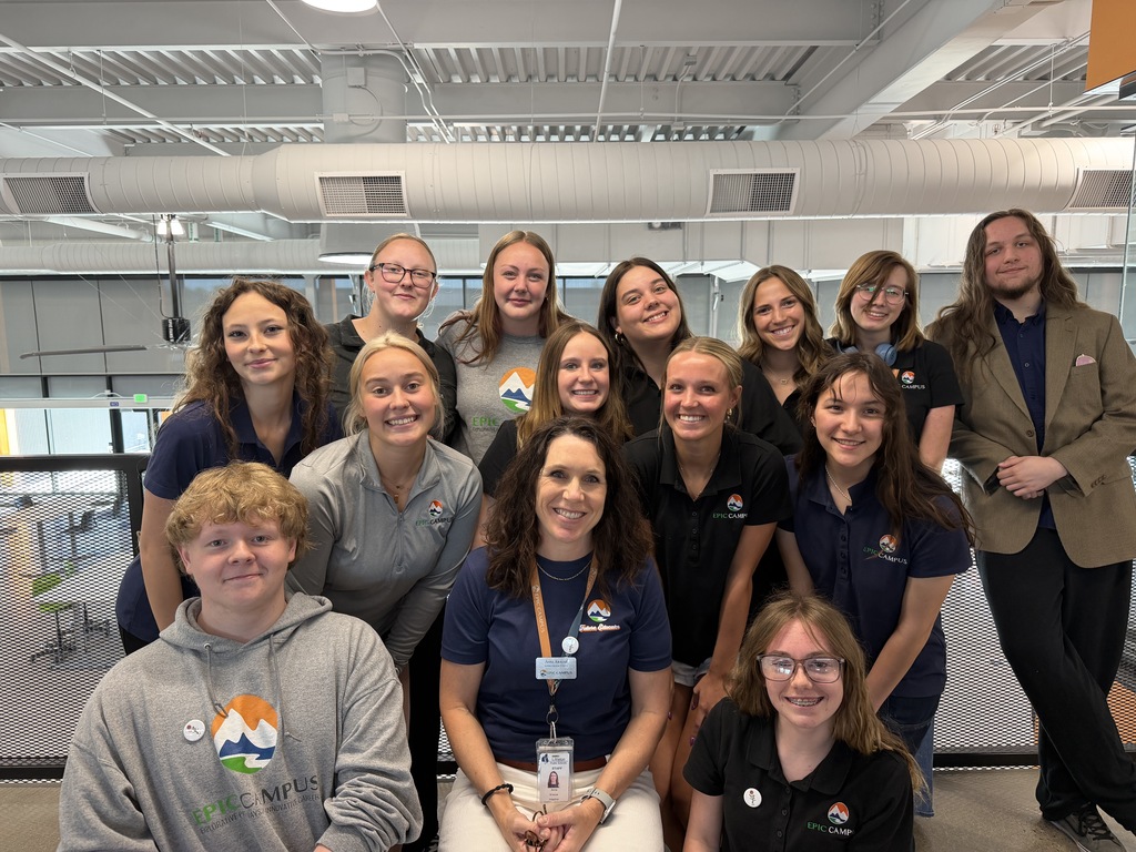 A group of adults in matching shirts poses for a photo inside a large room with glass walls.