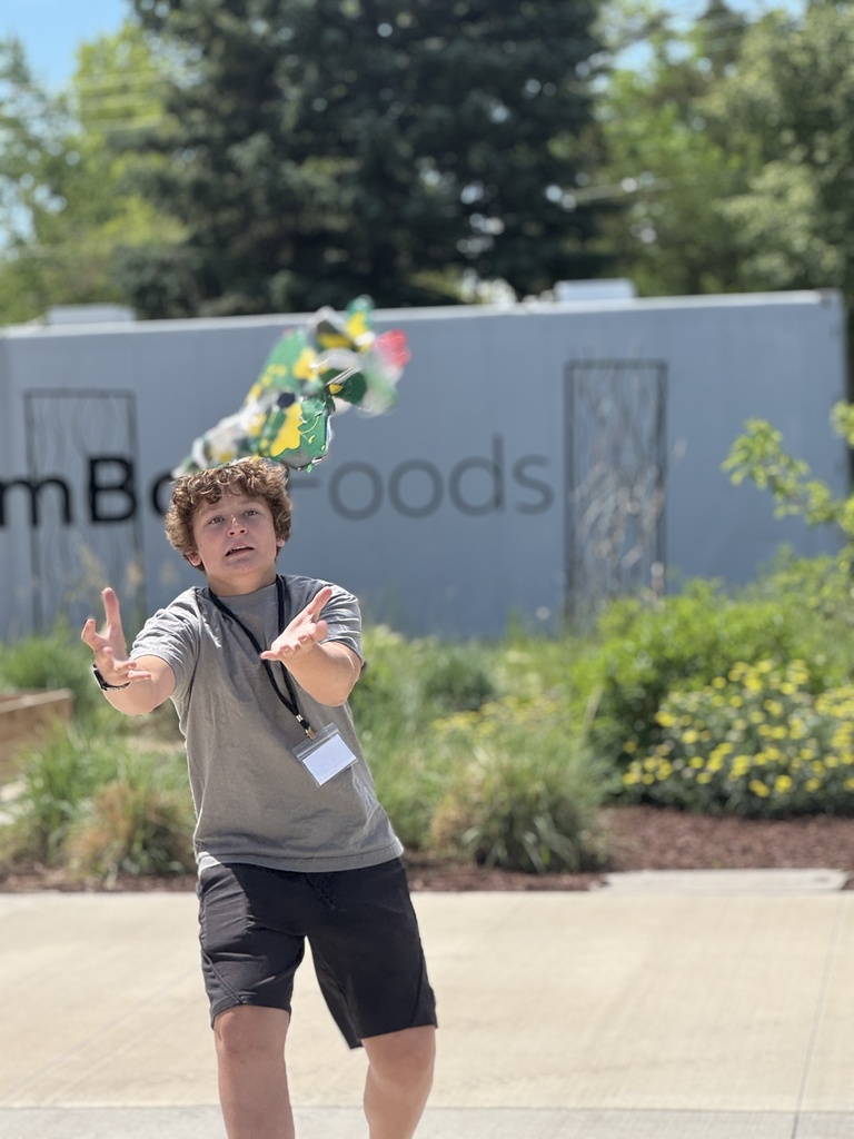 A person in a gray shirt and black shorts throws something in the air while standing outdoors.