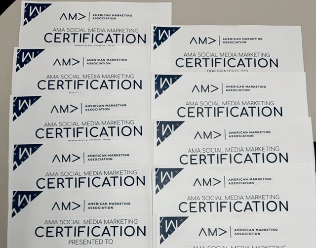 Certification documents for social media marketing from the American Marketing Association are stacked on a table.