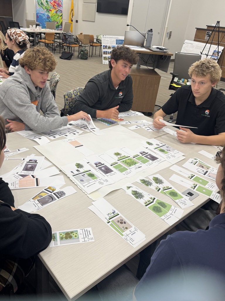 Four people at a table with papers, cards, and a map. Some are wearing polo shirts.