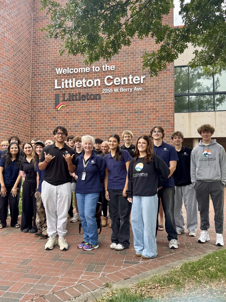 Group of individuals wearing uniforms standing in front of the Littleton Center, a brick building with a large sign.