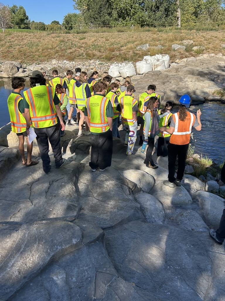 A group of people in reflective vests and hard hats are walking along a rocky path.