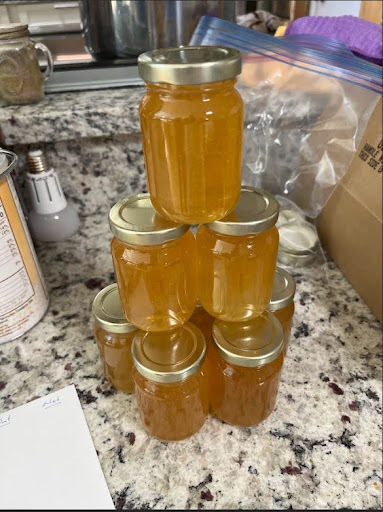 A small pyramid of glass jars filled with golden honey sits on a countertop. This honey was collected from the bee hives at EPIC Campus.