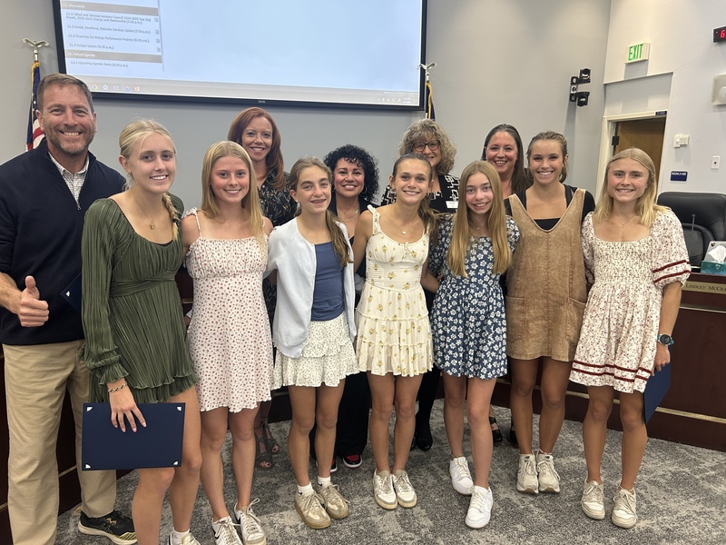 Photo of HHS's girls cross country team with the Board of Education in the Boardroom.