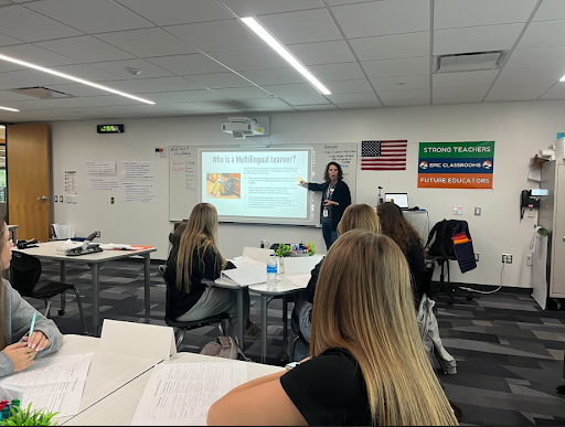 An educator is presenting a slide about "Who is a Multilingual Learner?" to a group of students in a classroom.