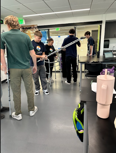 Several students in a classroom or lab adjusting crutches and a walker, indicating a practical lesson on mobility aids.
