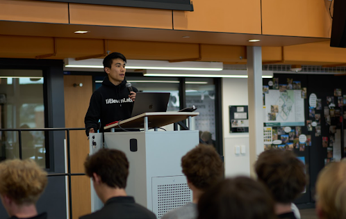 A close-up of a speaker at a podium addressing an audience with a microphone.