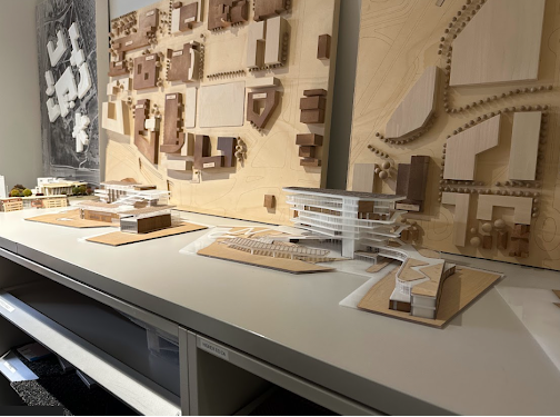 A display of several architectural and urban planning models on a long white table.