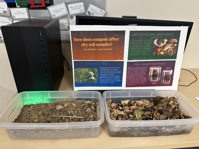 A close-up of a science display comparing dry soil samples and organic compost in plastic bins.