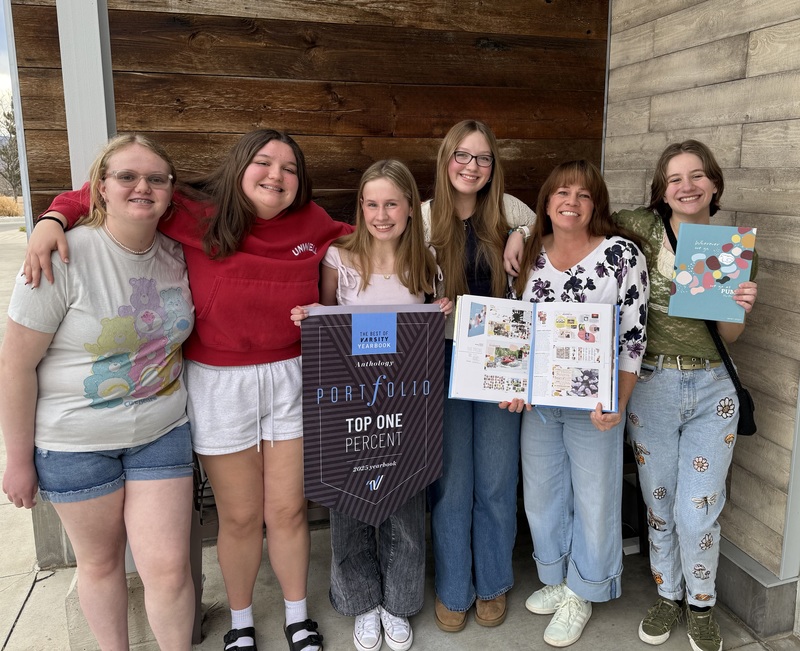 Five female students and their advisor hold up yearbook awards.