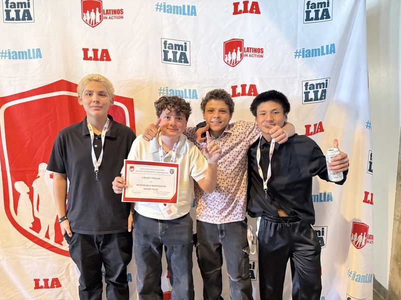 Four students pose together, one holding an "Honorable Mention in Short Film" certificate from Latinos In Action.