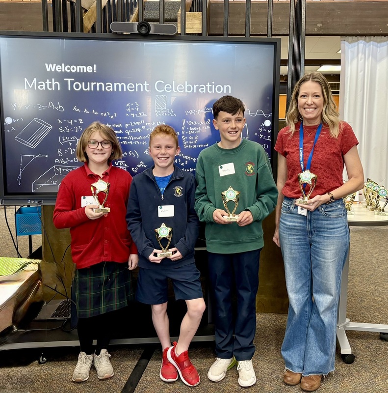 Three Littleton Academy 4th graders and their teacher pose with trophies at the Math Tournament Celebration.