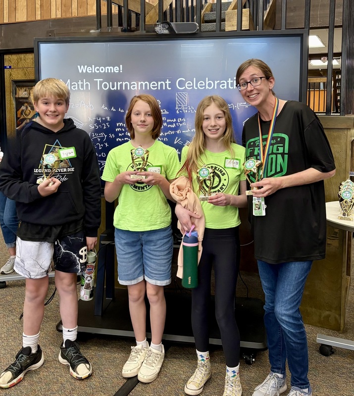 Three Hopkins Elementary 5th graders and their teacher pose with trophies at the Math Tournament Celebration.