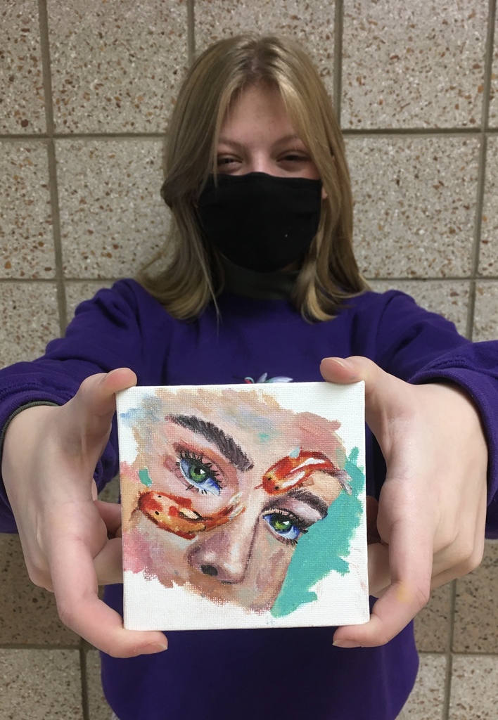 female student holding a painting of a face with fish