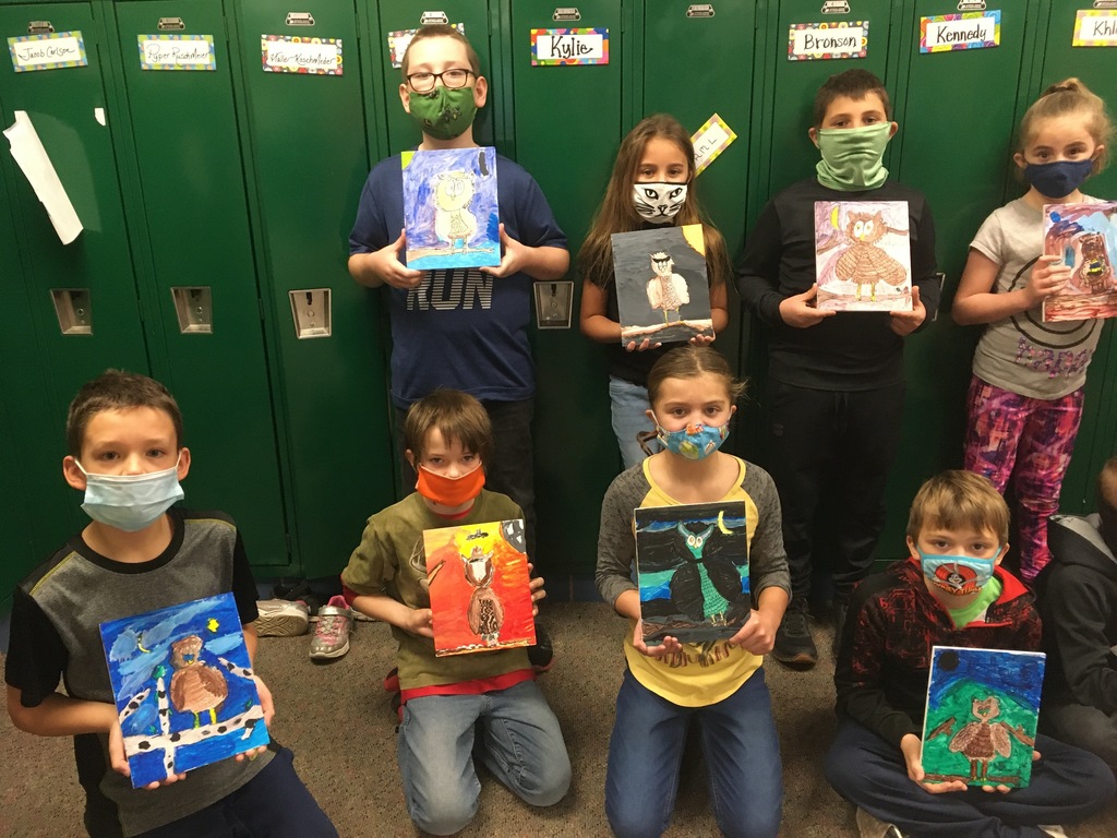 male and female students holding owl paintings