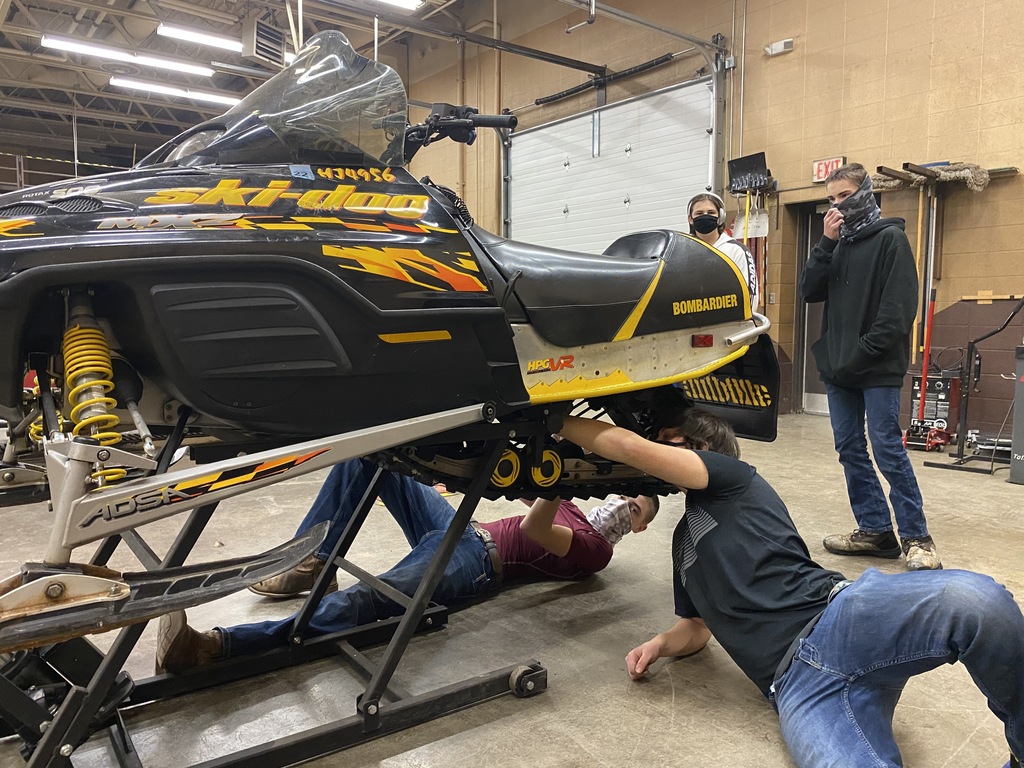 4 male students working on a snowmobile