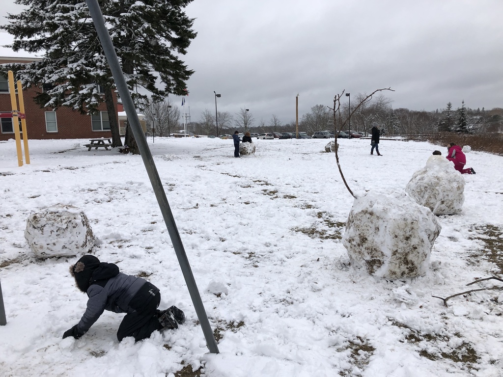 Children roll a snow boulder