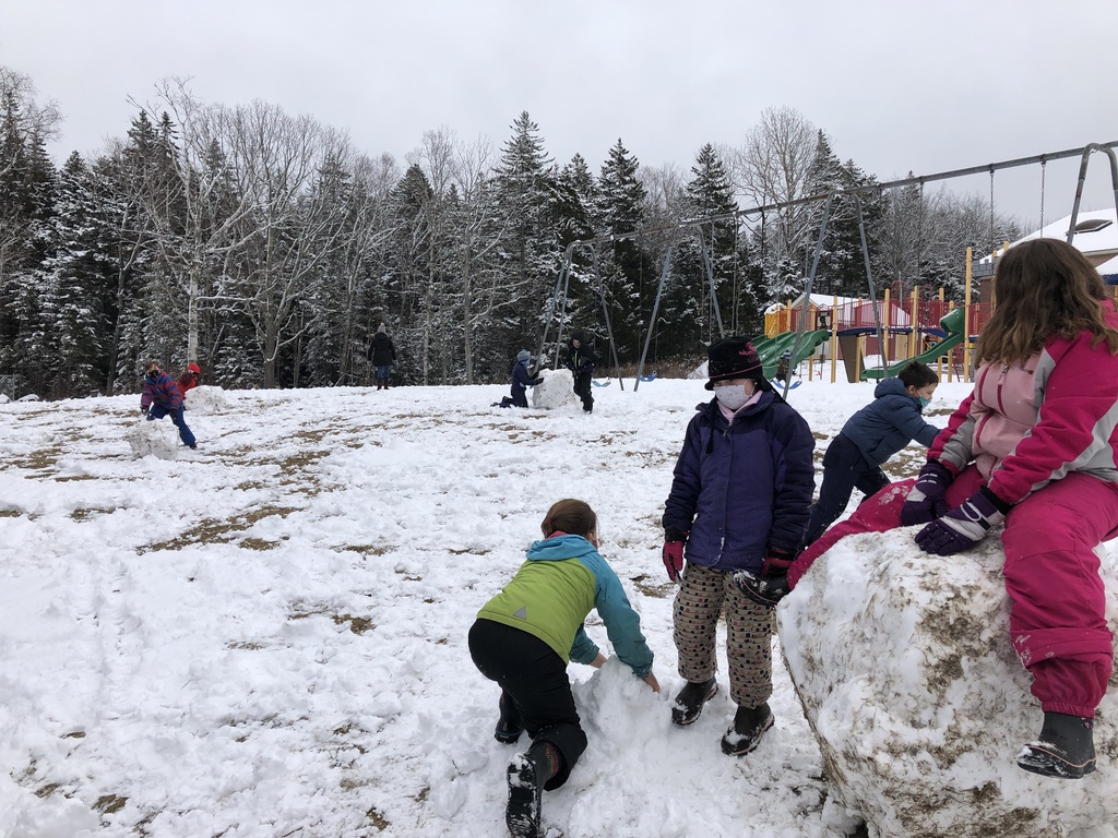 Children roll and sit on snow boulders