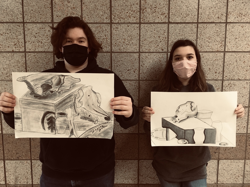 male and female student holding charcoal still-life paintings