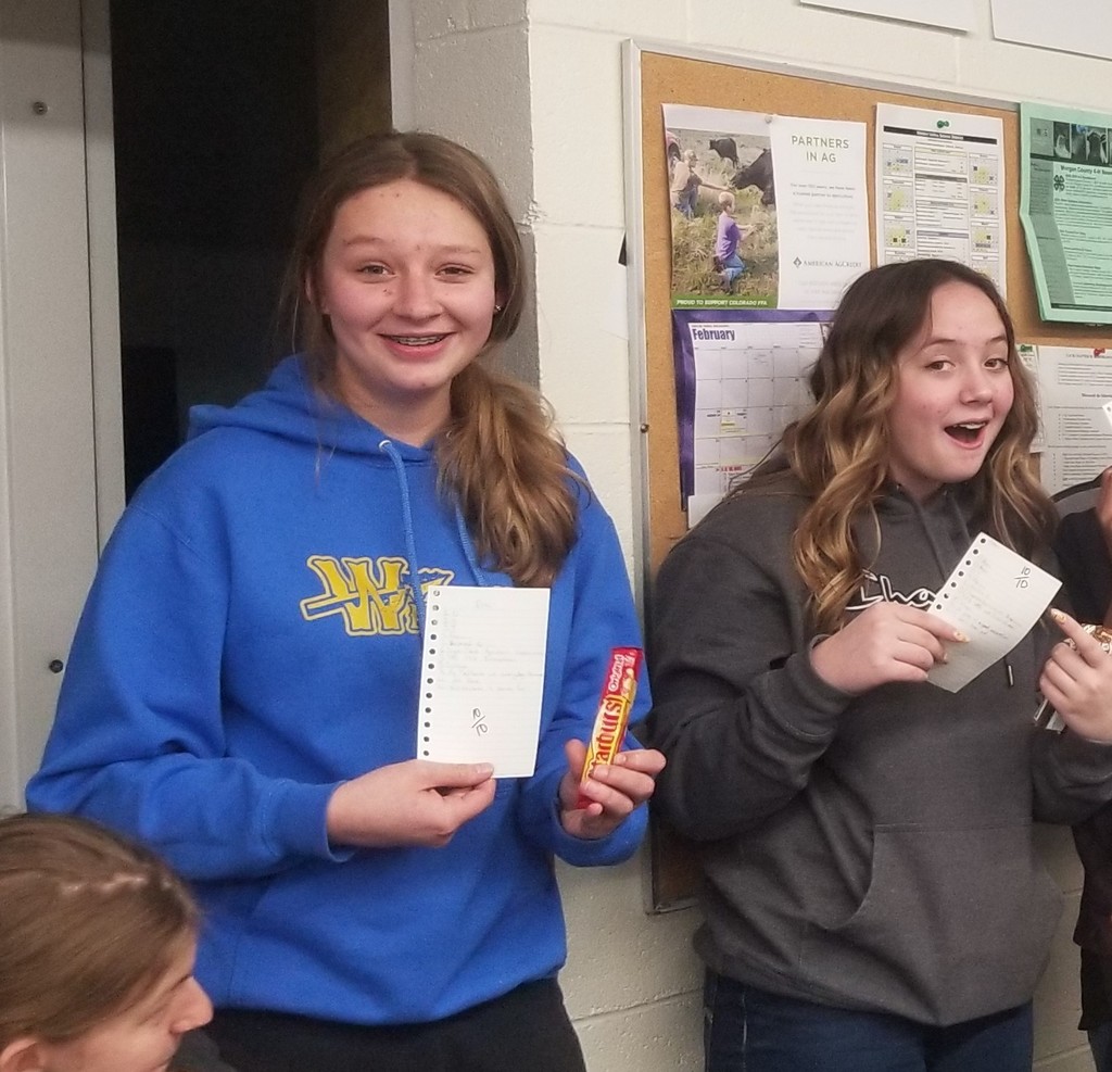 More Students who won a prize showing their scored test paper and candy bar