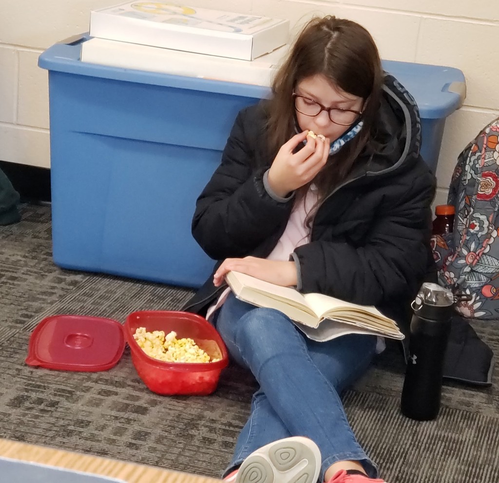 6th grade girl reads book while eating popcorn