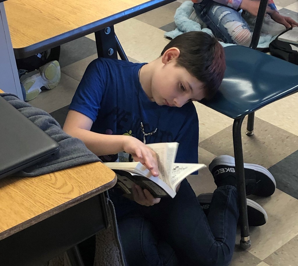 Boy sits on floor reading a book