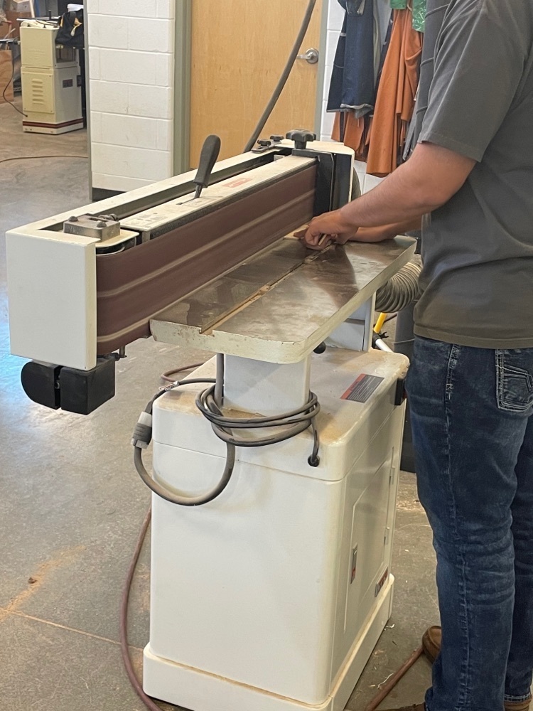 Student using a sanding machine. 