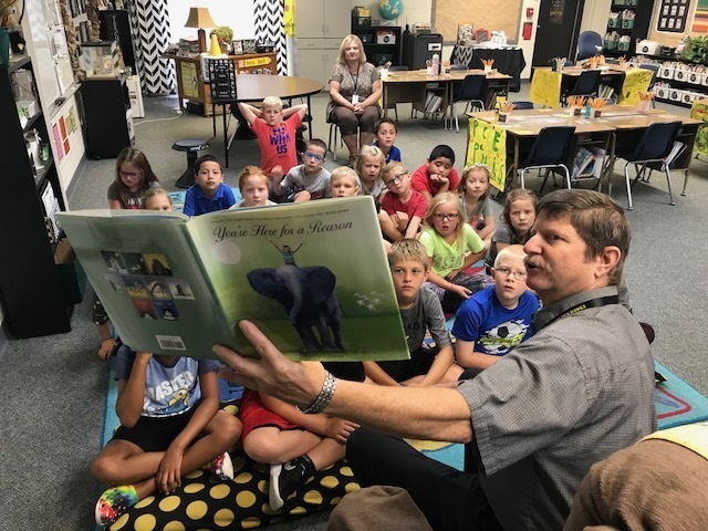 Mark Schneider, superintendent, holds up a book while reading to second graders during National Read a Book Day