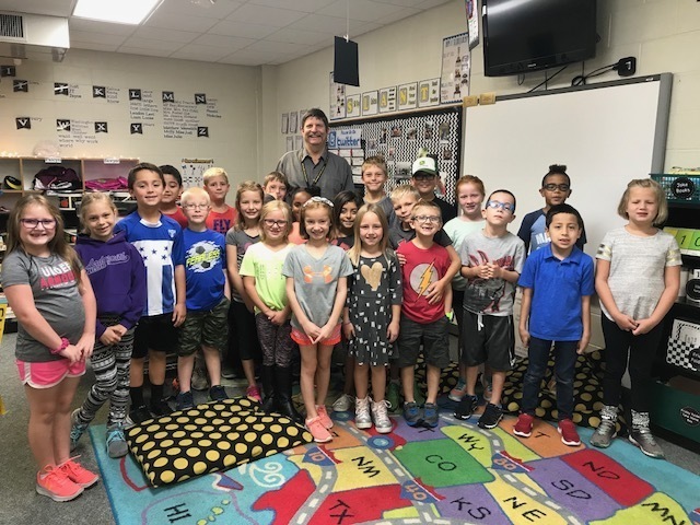 Mrs. Bell's class gathers around Superintendent Mark Schneider after listening to him read a book on National Read a Book Day