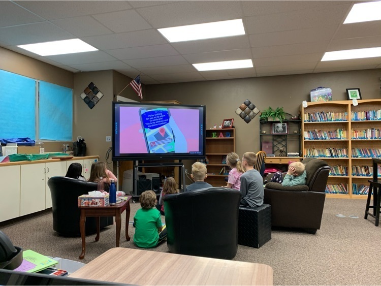 Students sitting around a big TV watching a video about responsible use of technology.