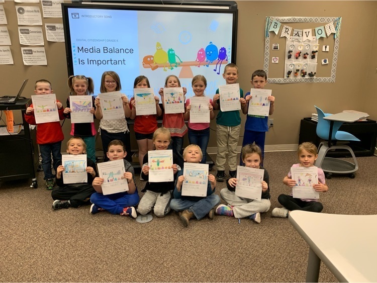A kindergarten class holding up their complete worksheet to show off their drawing about media balance.