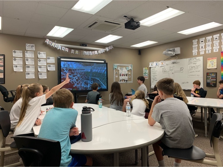 Students sitting in a classroom watching another student present his battleship game he created.