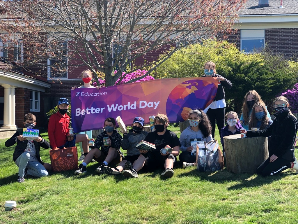 Students sit outside on lawn with donated books and food