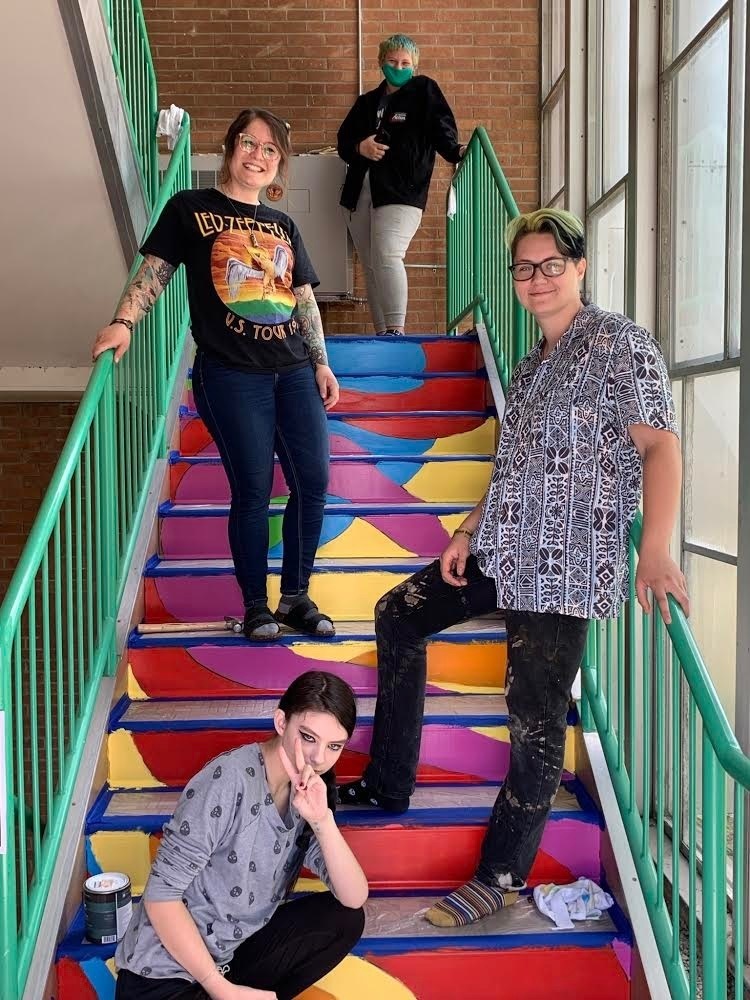 artist and students working on community center/RHS stairwell painting